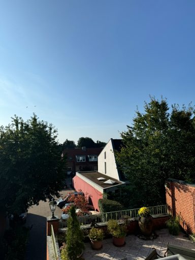 Heller Himmel über einer Wohnsiedlung mit Häusern und grünen Bäumen.