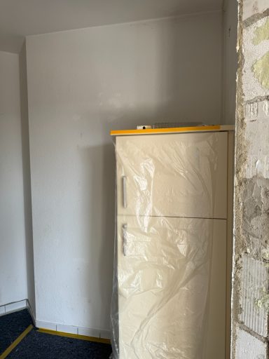 Leichter PVC-Boden mit einem weißen Kühlschrank in einer ungepflegten Ecke.