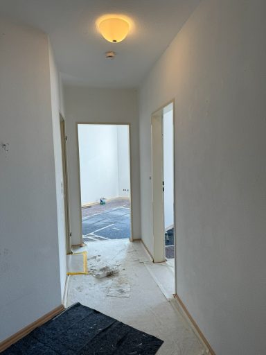 Heller Flur mit Türen zu weiteren Räumen und einem Teppichboden am Ende.