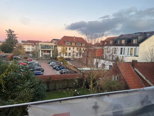 Blick auf eine Wohnsiedlung mit Autos, Bäume und einen Sonnenuntergang.